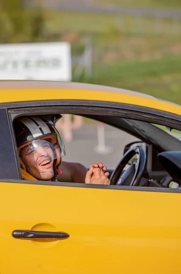 Jeune homme souriant au volant avec son casque lors d'une journée circuit