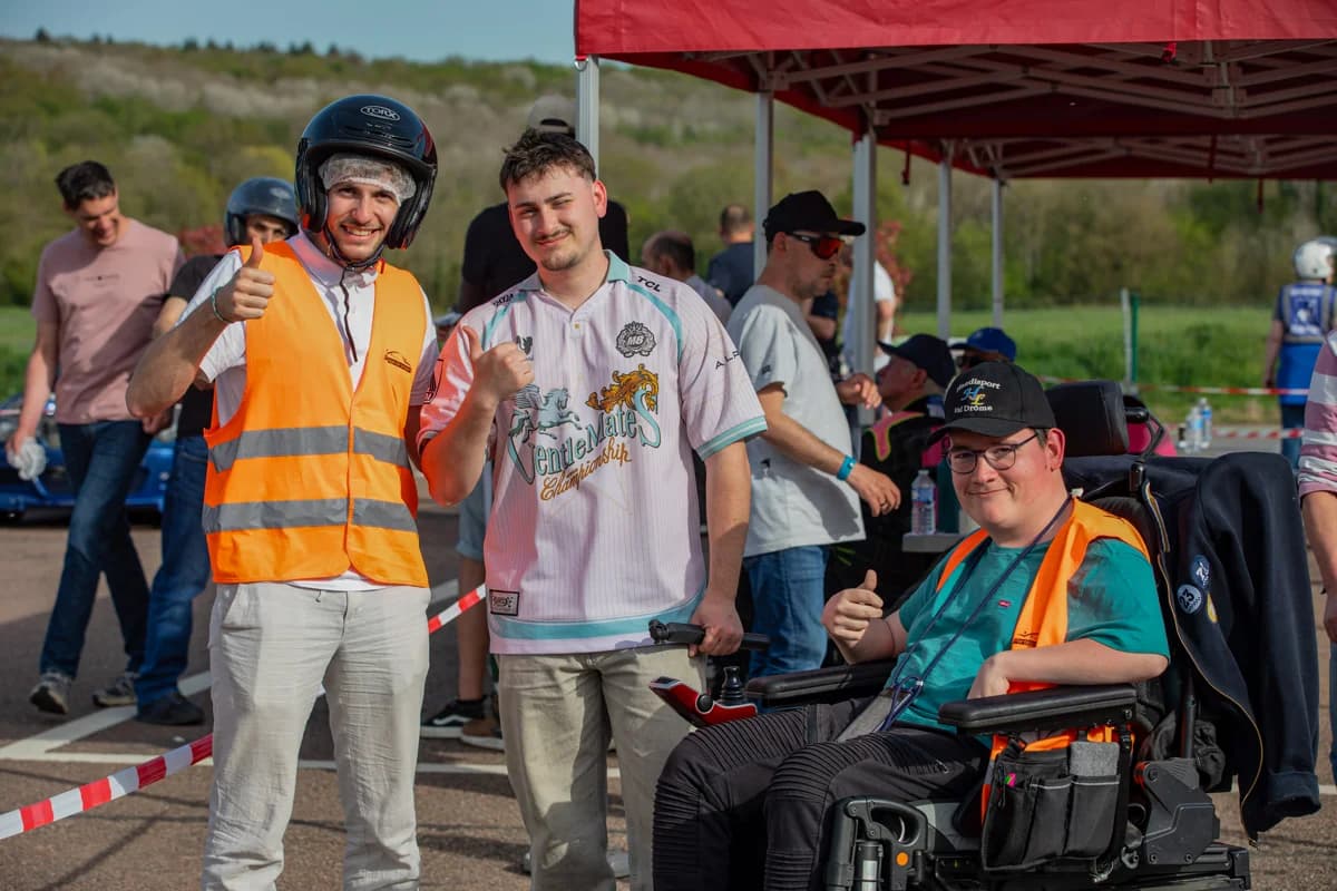 Trois participants souriants dont une personne en fauteuil roulant lors d'une journée circuit